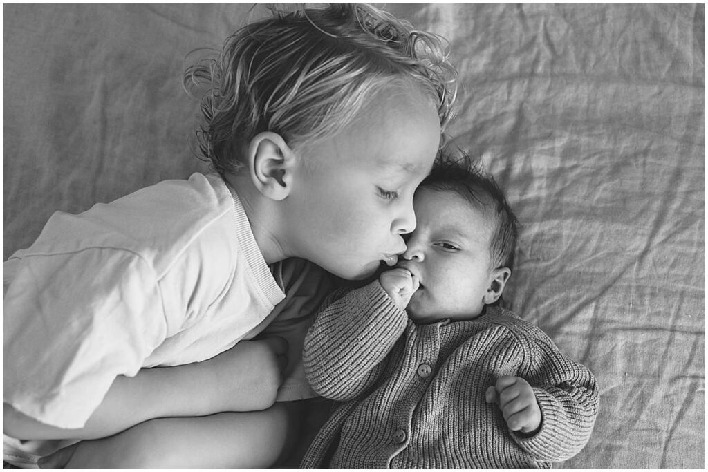Broer geeft zijn zusje een kusje tijdens een newborn fotoshoot in Amersfoort