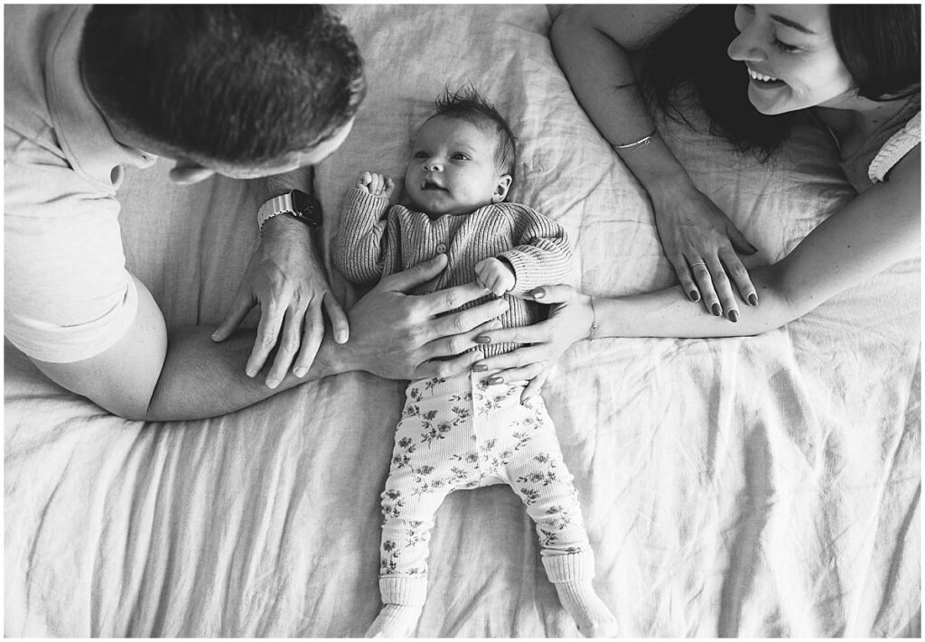 trotse ouders met baby op bed tijdens een fotoshoot in amersfoort